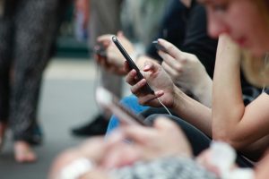 Verschiedene Menschen sitzen mit ihren Smartphones. 