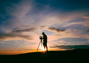 Silhouette Mann mit Kamera bei einem Sonnenaufgang.