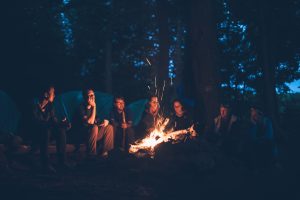 Menschen sitzen bei Nacht am Lagerfeuer. 